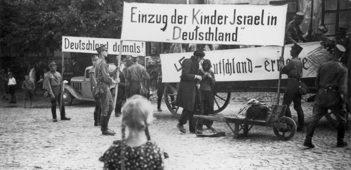 A young girl watches a Nazi antisemitic parade.